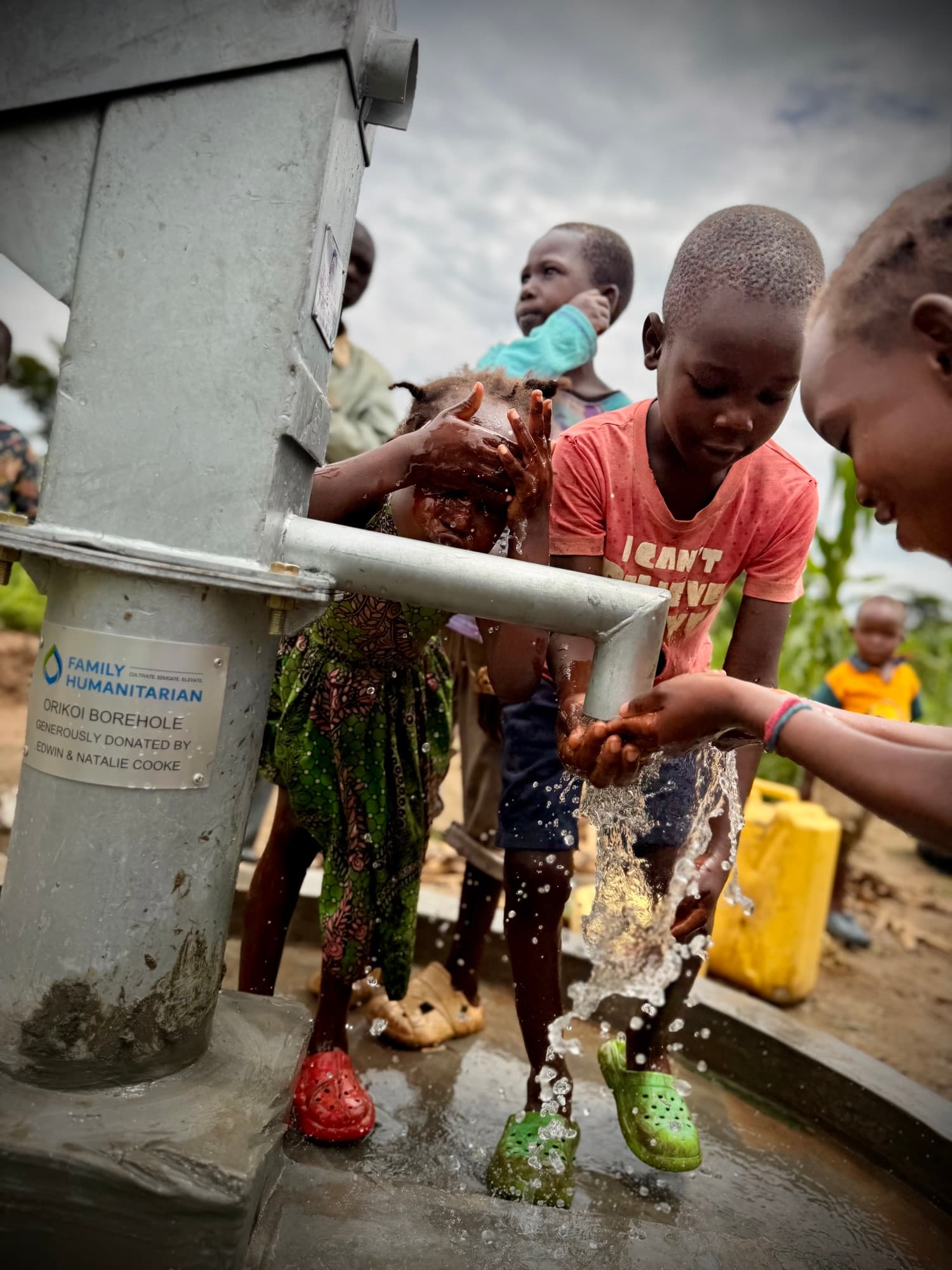 Children washing their hands and faces in water flowing from the Orikoi borehole hand pump