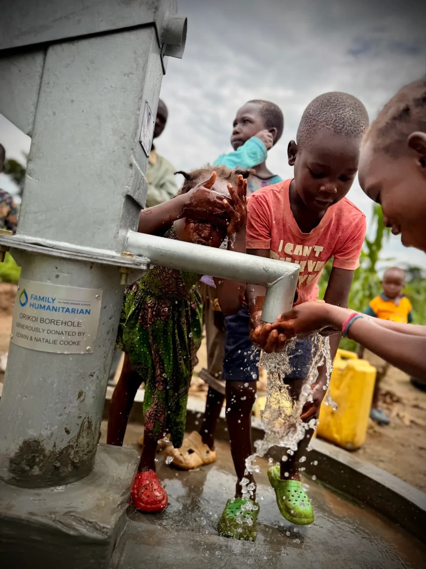 Children washing their hands and faces in water flowing from the Orikoi borehole hand pump